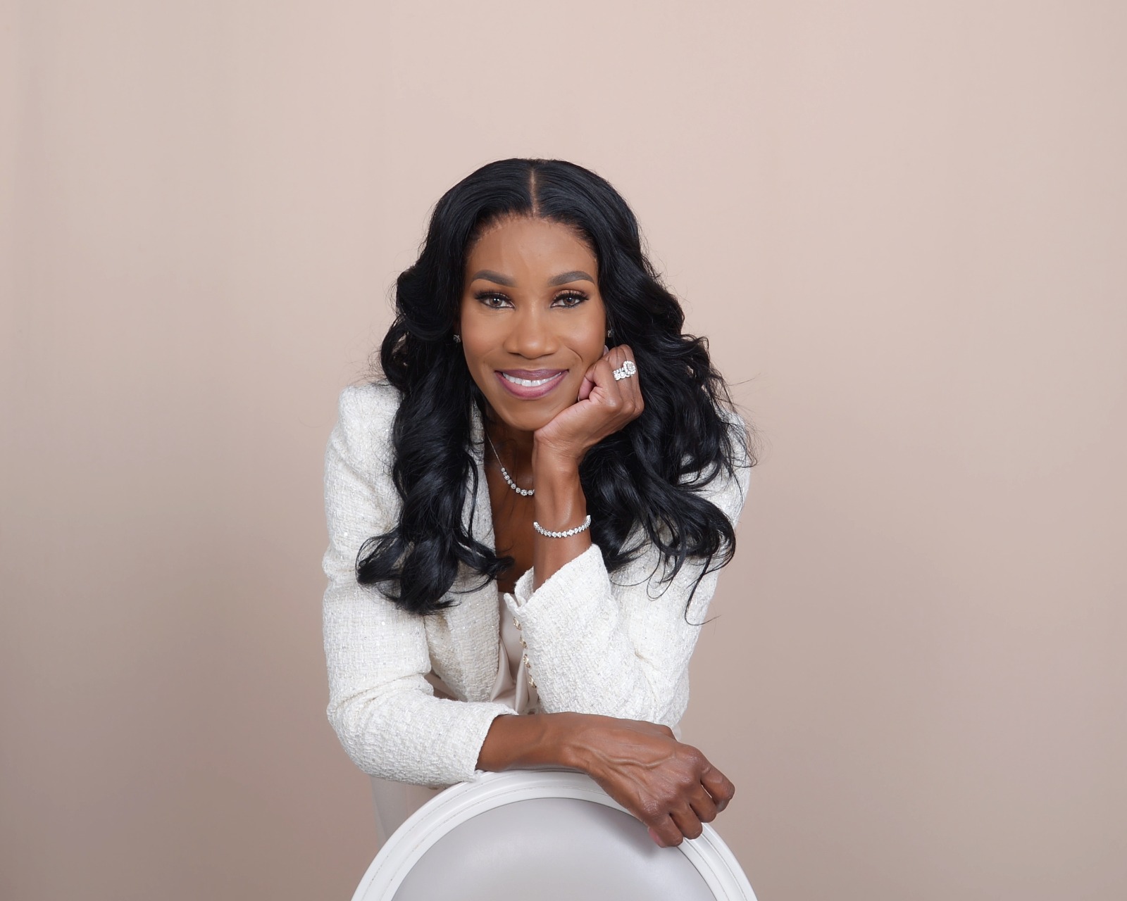 Lady Michelle smiling in an ivory jacket, seated against a warm neutral backdrop